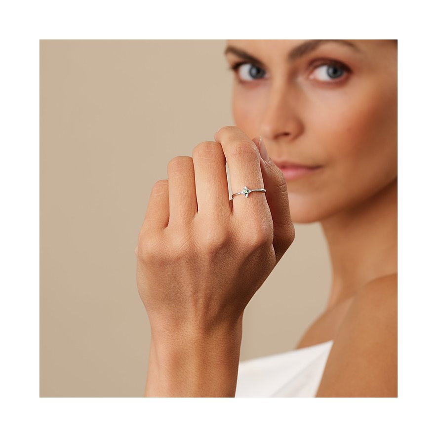 Nahaufnahme eines goldenen CHRIST Rings aus 375er Weißgold mit Granat-Farbstein am Finger einer Frau.