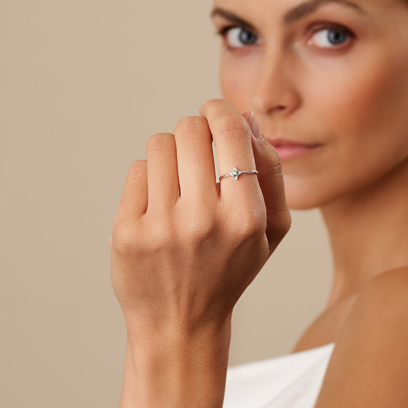 Nahaufnahme eines goldenen CHRIST Rings aus 375er Weißgold mit Granat-Farbstein am Finger einer Frau.