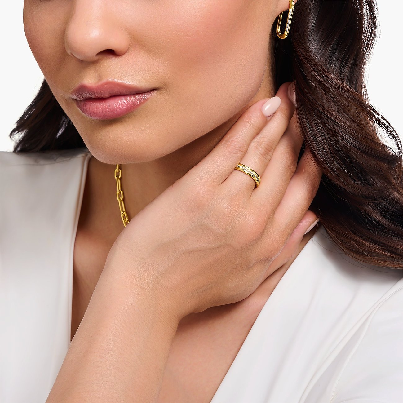 Eine Frau trägt einen goldenen Thomas Sabo Silberring mit Zirkonia, der auf dem Finger zu sehen ist.