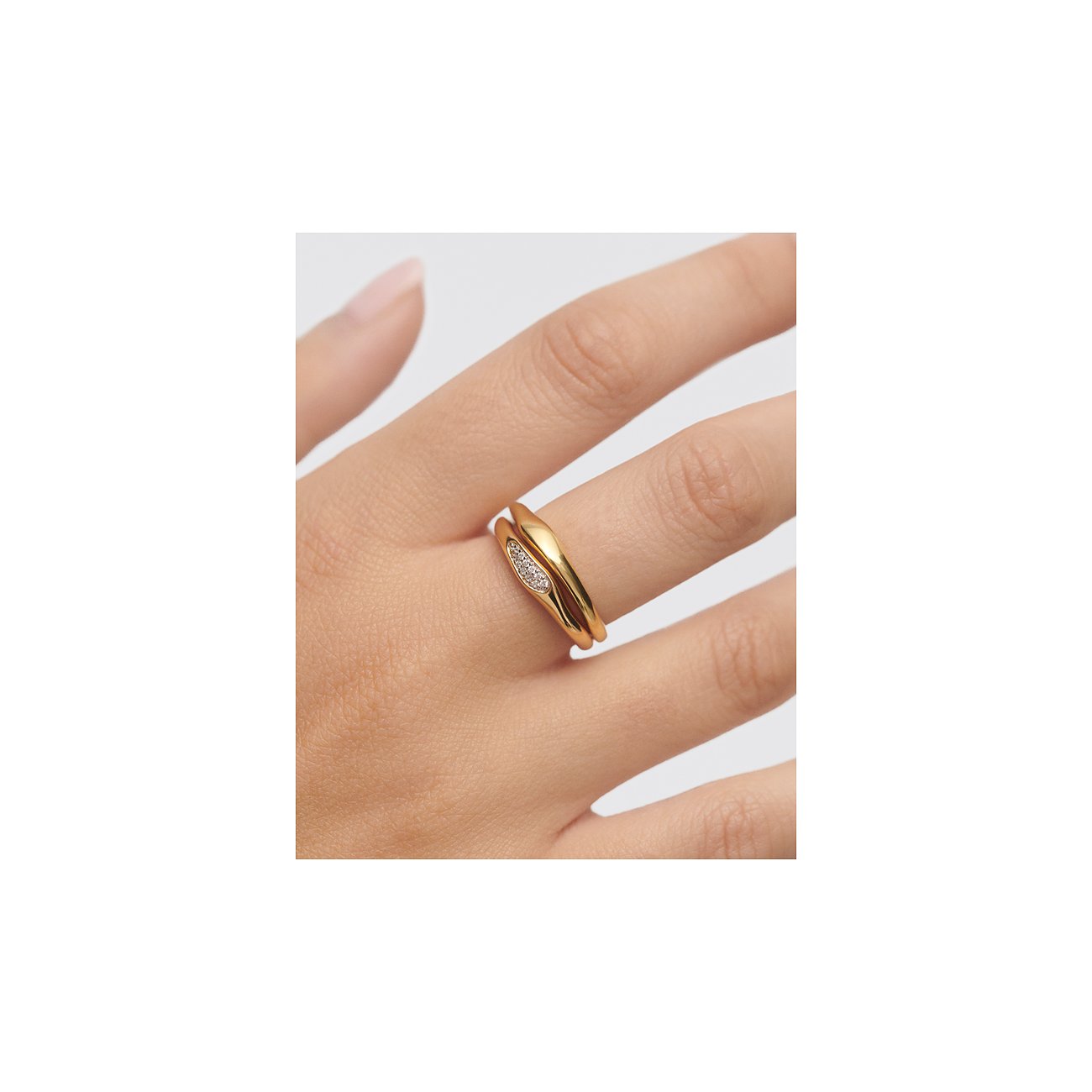 Am Ringfinger einer Person ist ein PdPaola goldener 925 Silberring zu sehen, der mit klaren Zirkonia Steinen besetzt ist.