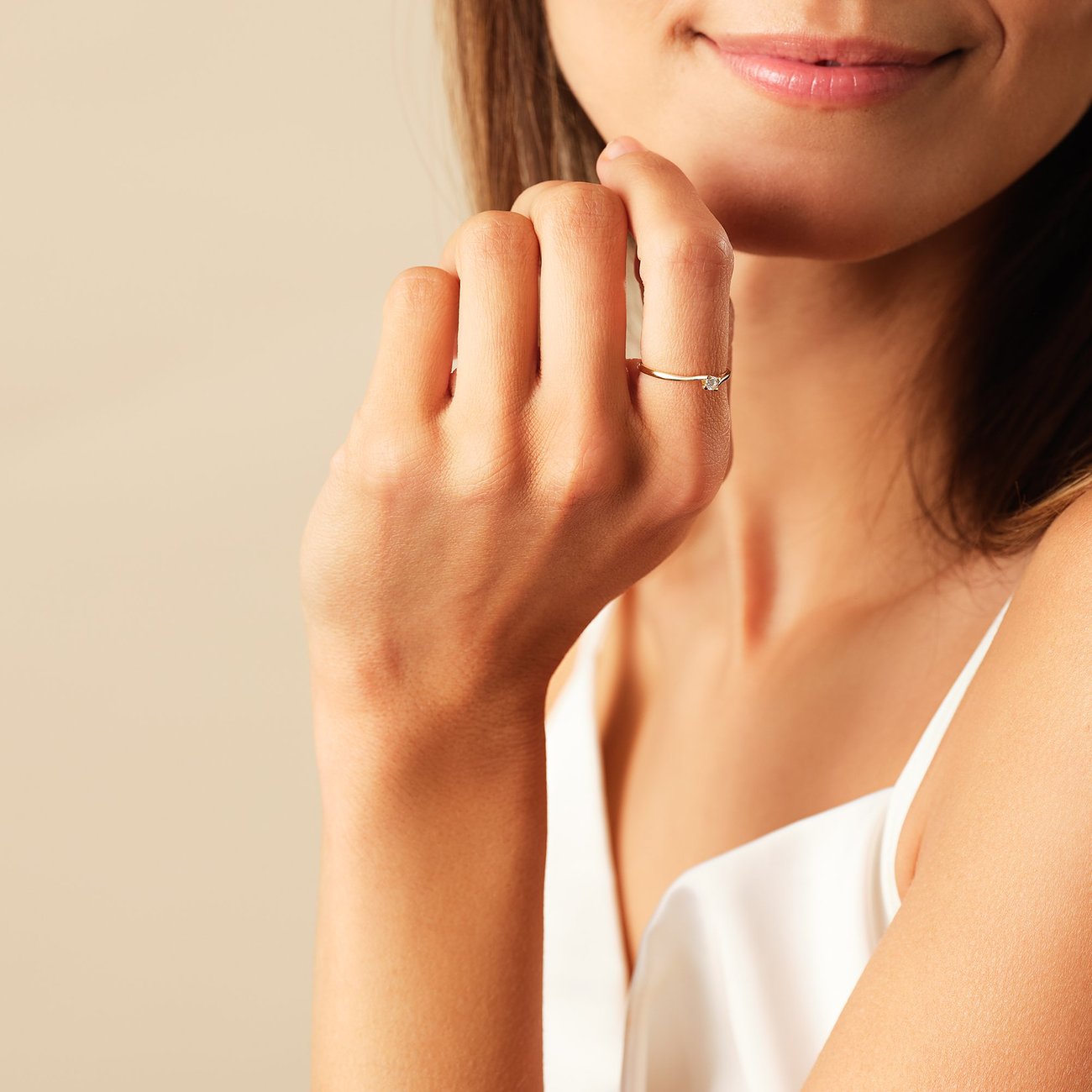 Eine Frau trägt einen CHRIST 585 Gelbgold Ring mit Diamantstein am Ringfinger, die Hand liegt am Kinn.
