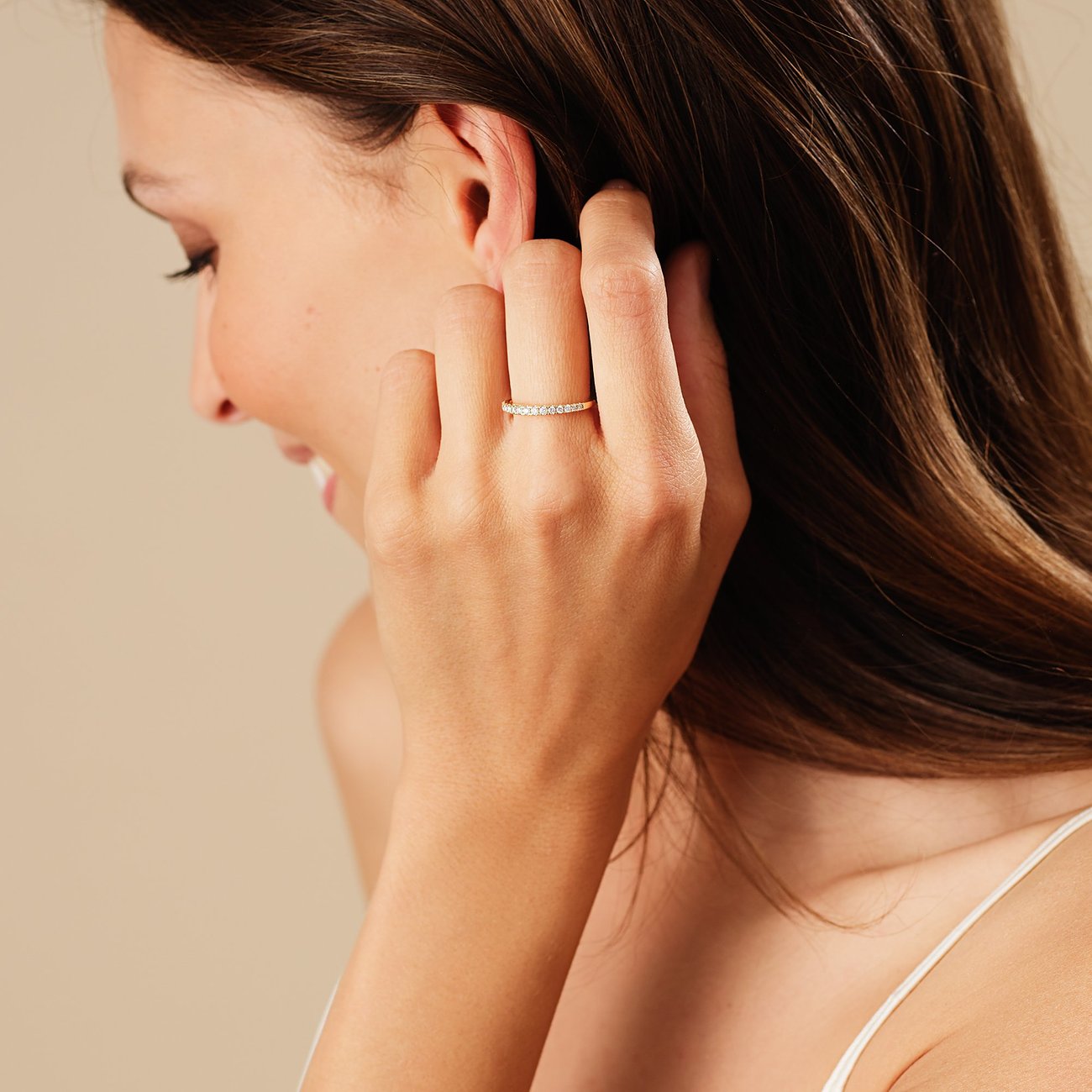 Eine Frau trägt einen CHRIST 585 Gelbgold Ring mit funkelnden Diamanten am Ringfinger, während sie sich ans Ohr fasst.