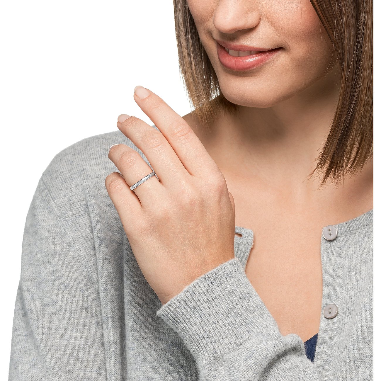 Eine Frau trägt einen schlichten CHRIST Ring aus Weißgold an ihrem Ringfinger, gesehen aus leicht schräger Vorderansicht.