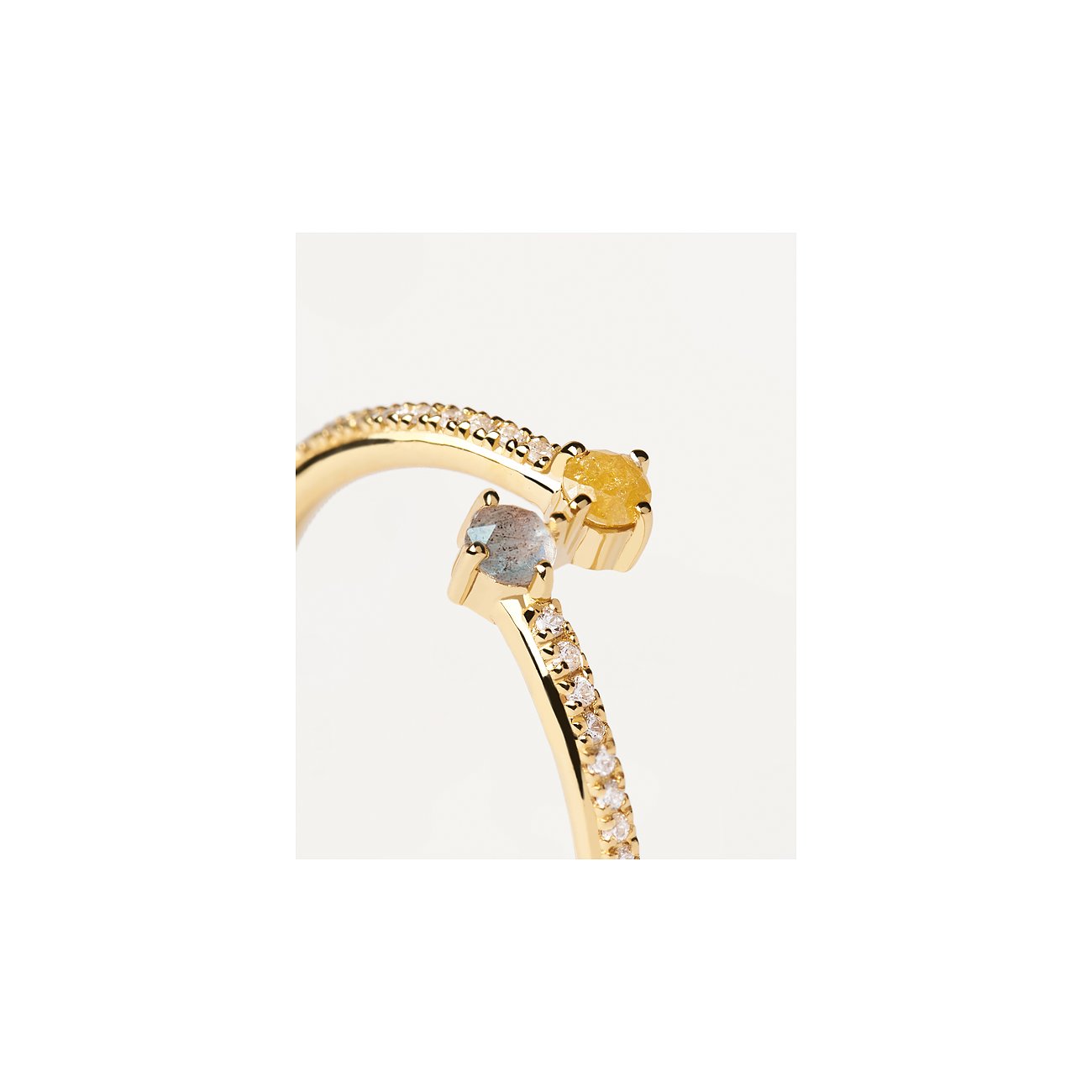 Nahaufnahme eines goldenen PdPaola Rings aus 925er Silber mit Labradorit und weiteren Farbedelsteinen, der sich um den Finger wickelt.