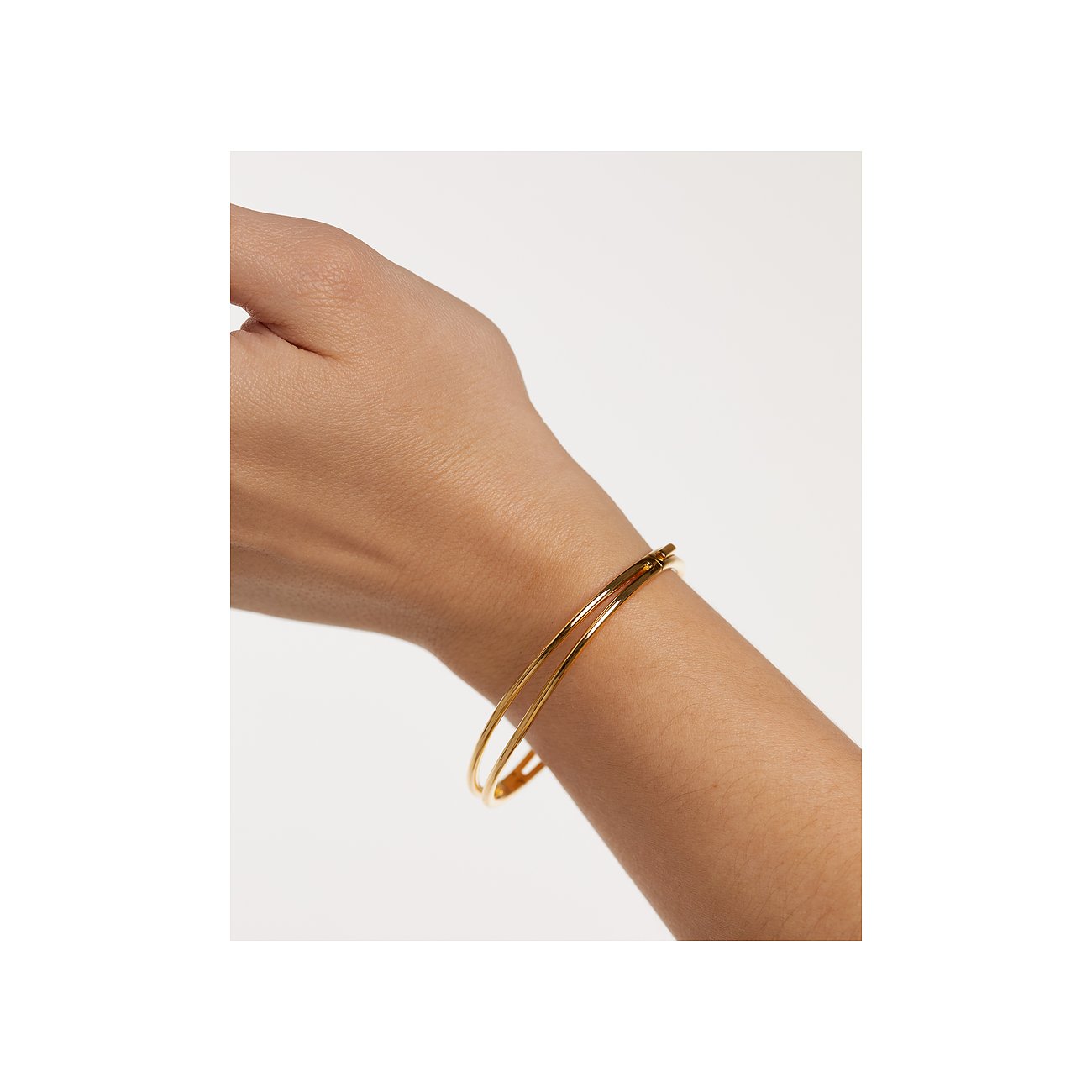Ett PdPaola armband i förgyllt silver vilar elegant runt en modells handled.