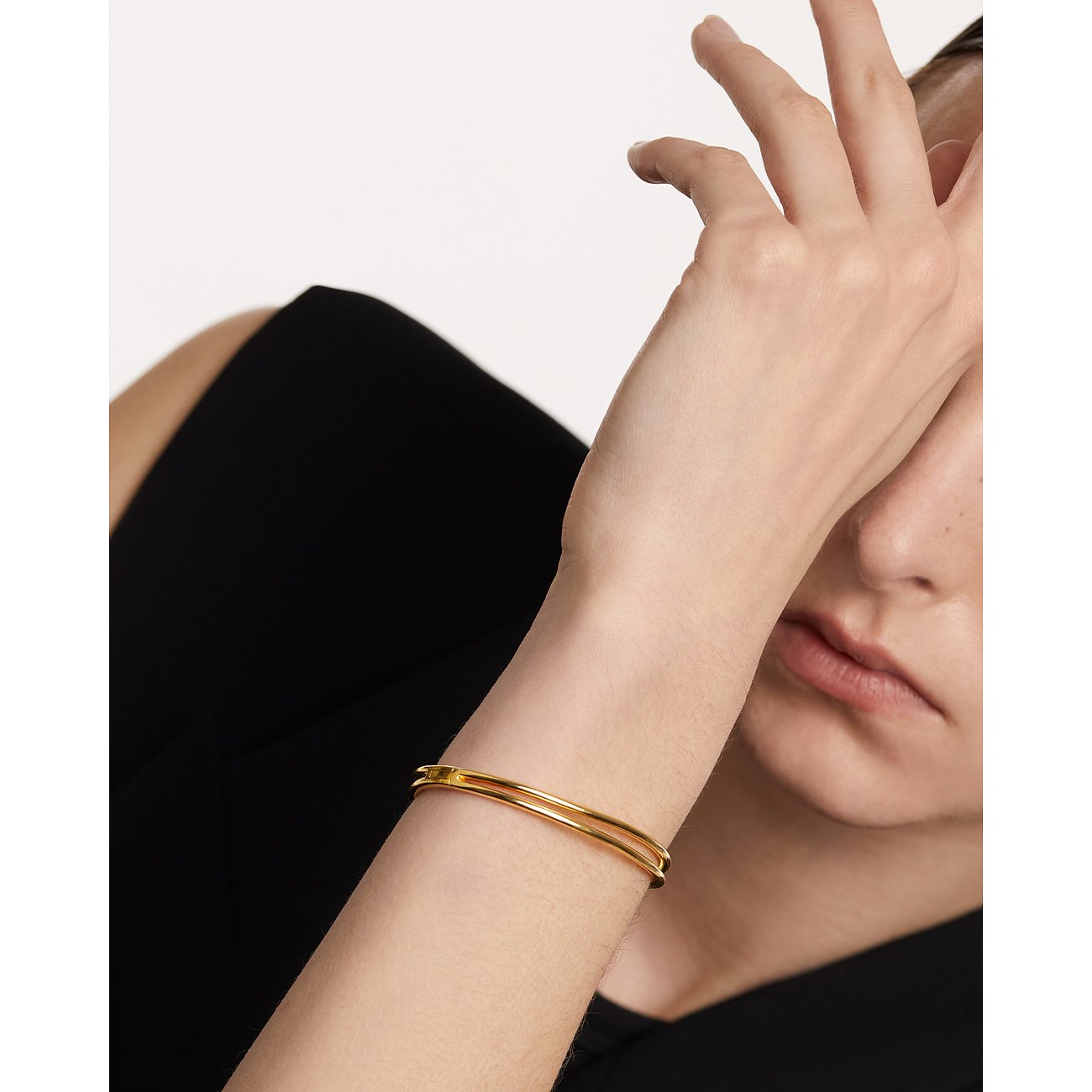 Guld PdPaola armband i sterlingsilver buret på en persons handled mot en vit bakgrund.