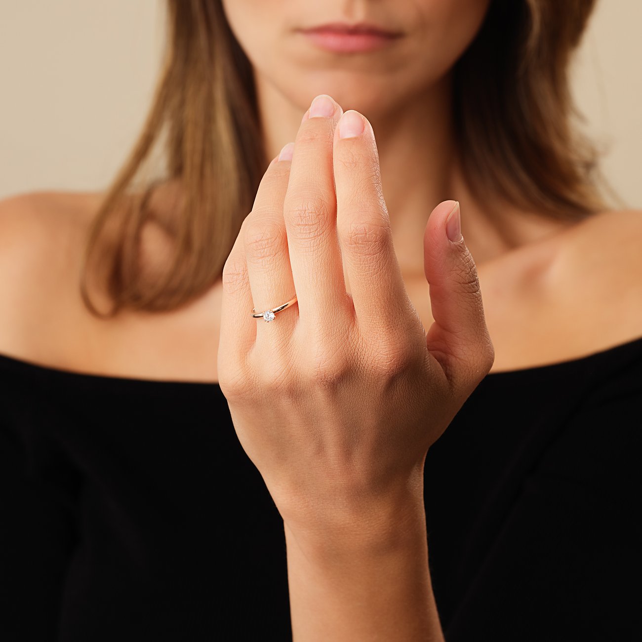Ein zarter CHRIST Solitaire-Ring aus 585 Roségold mit einem funkelnden Diamanten am Finger einer Frau.