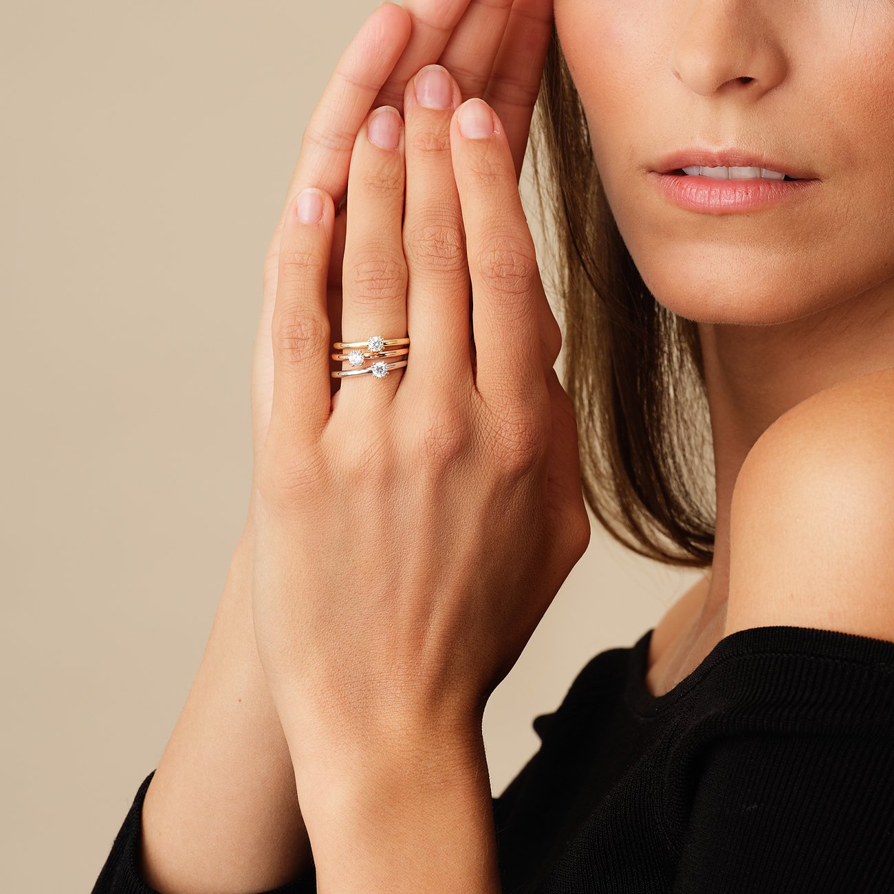 Nahaufnahme einer Frau, die drei CHRIST Diamantringe an einem Finger trägt, zwei aus Roségold und einer aus Weißgold.