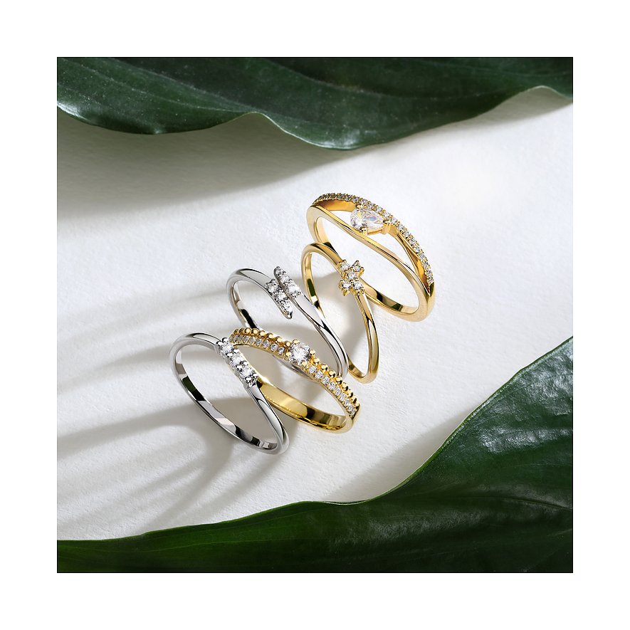 Live Diamond Ringe aus Gelbgold und silberfarbenem Metall, besetzt mit Diamanten, auf weißem Hintergrund mit grünen Blättern.