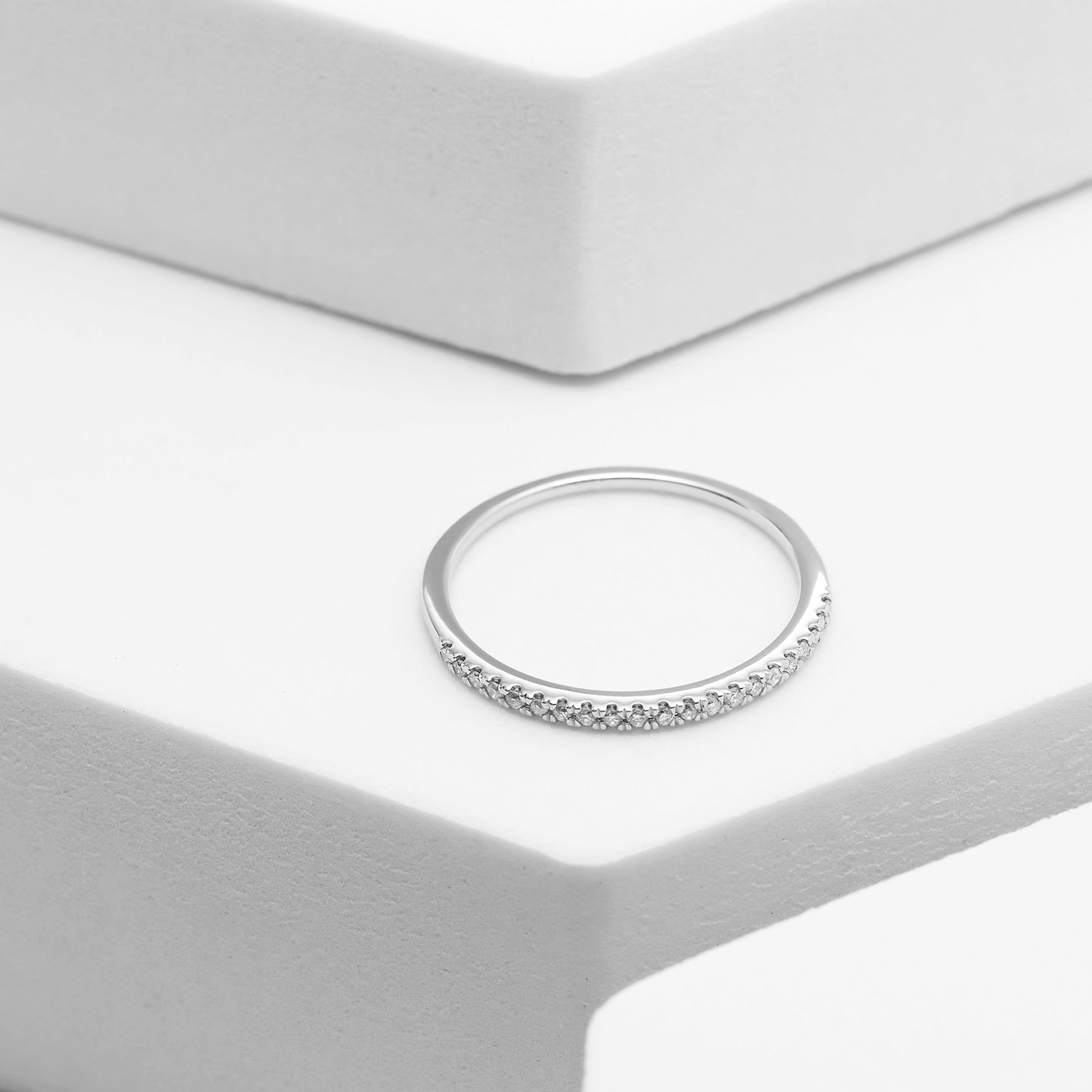 Ein zarter Ring aus 585er Weißgold, besetzt mit funkelnden Diamanten, der elegant auf einer weißen Oberfläche liegt.