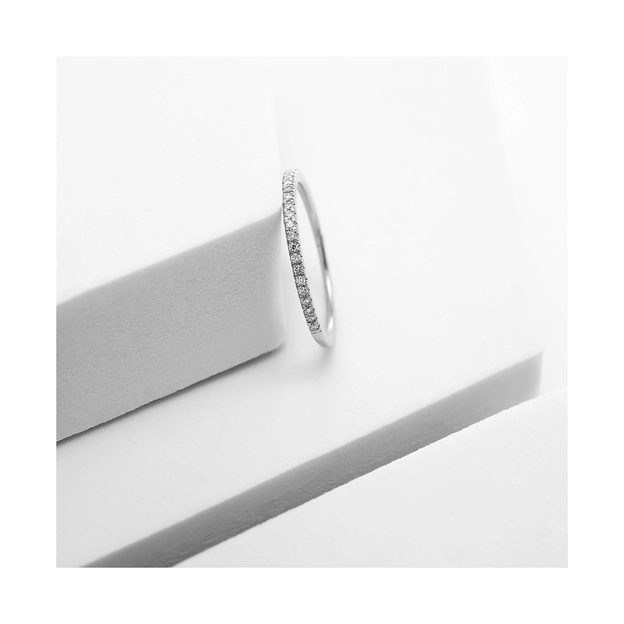 Weißgoldring, besetzt mit funkelnden Diamanten, der elegant auf einer stilisierten weißen Oberfläche liegt.