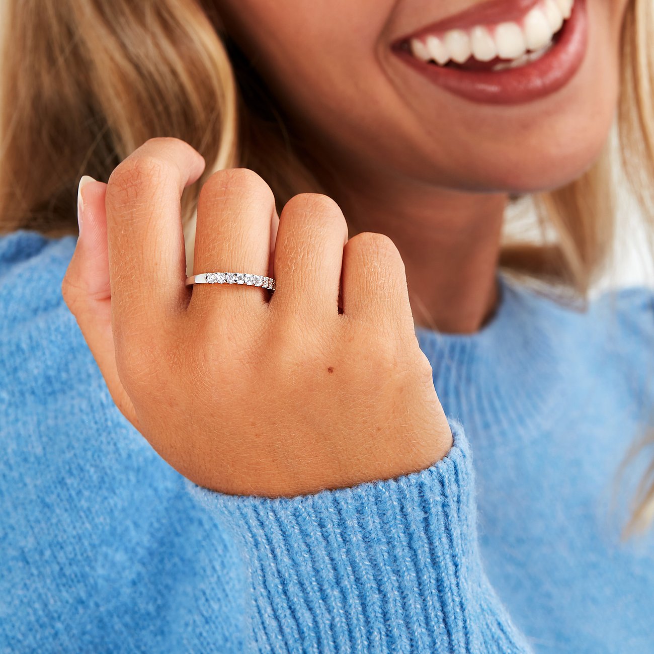 Nahaufnahme eines CHRIST 585er Weißgold-Rings mit Diamanten, getragen an einer Hand mit blauem Pullover.