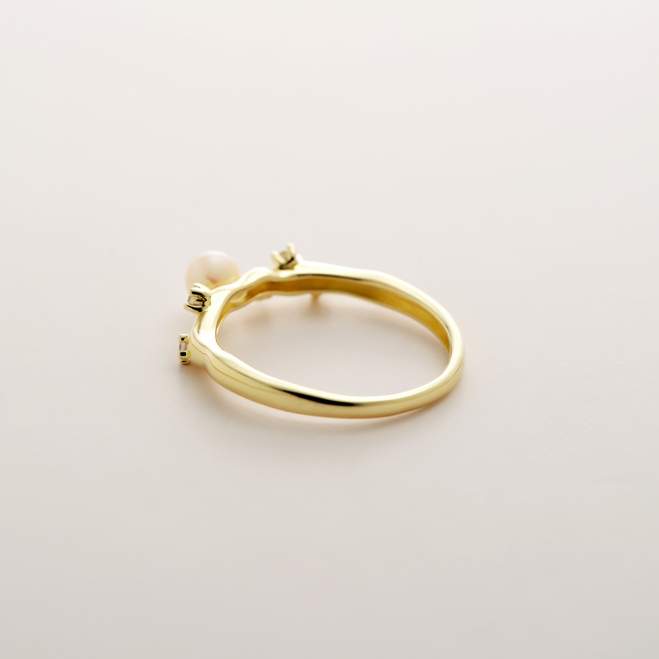 YAMOKO Ring aus 585 Gelbgold mit einer Perle und zwei kleinen Akzentsteinen, schräg von hinten fotografiert.
