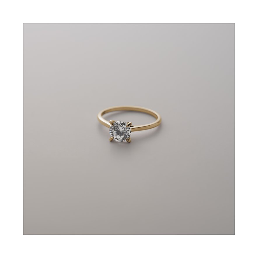 CHRIST Ring aus Gelbgold mit funkelndem Diamanten in Krappenfassung, auf glatter, grauer Oberfläche im Freisteller