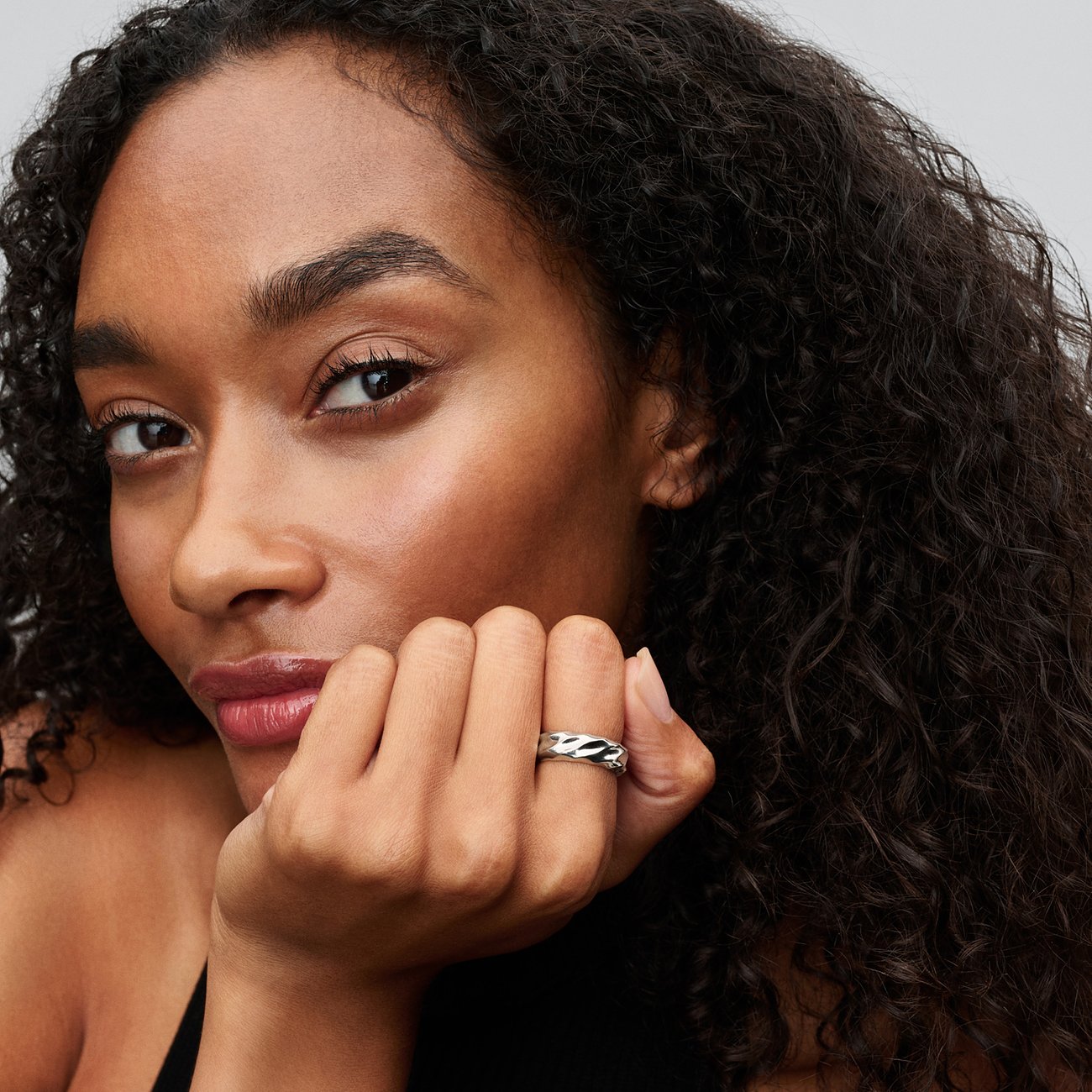 Eine Frau trägt einen silbernen Pandora Ring aus 925er Silber mit wellenförmigem Design am Ringfinger.
