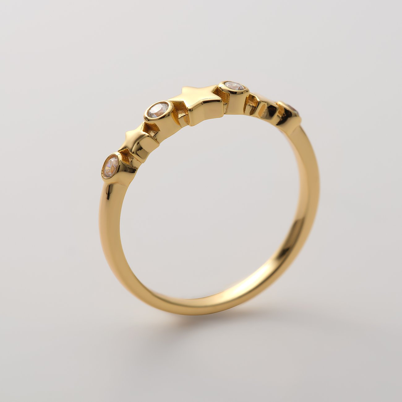 CHRIST ring i förgyllt återvunnet silver med stjärnmönster och klara zirkoniastenar, snett uppifrån.