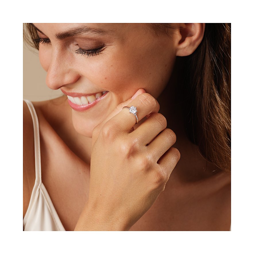 Eine Nahaufnahme zeigt eine lächelnde Frau, die einen CHRIST Ring aus 585 Weißgold mit einem Diamanten trägt.