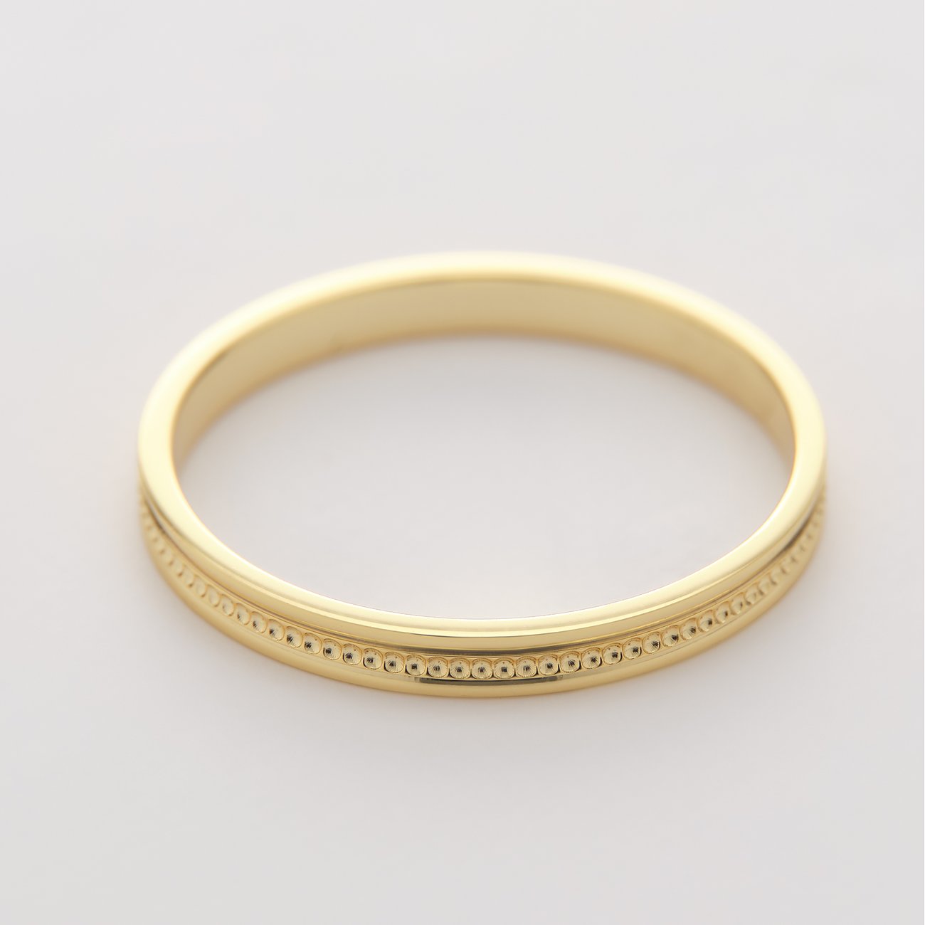 Ein glänzender goldfarbener CHRIST Ring aus recyceltem Silber mit einem zarten, punktierten Muster.