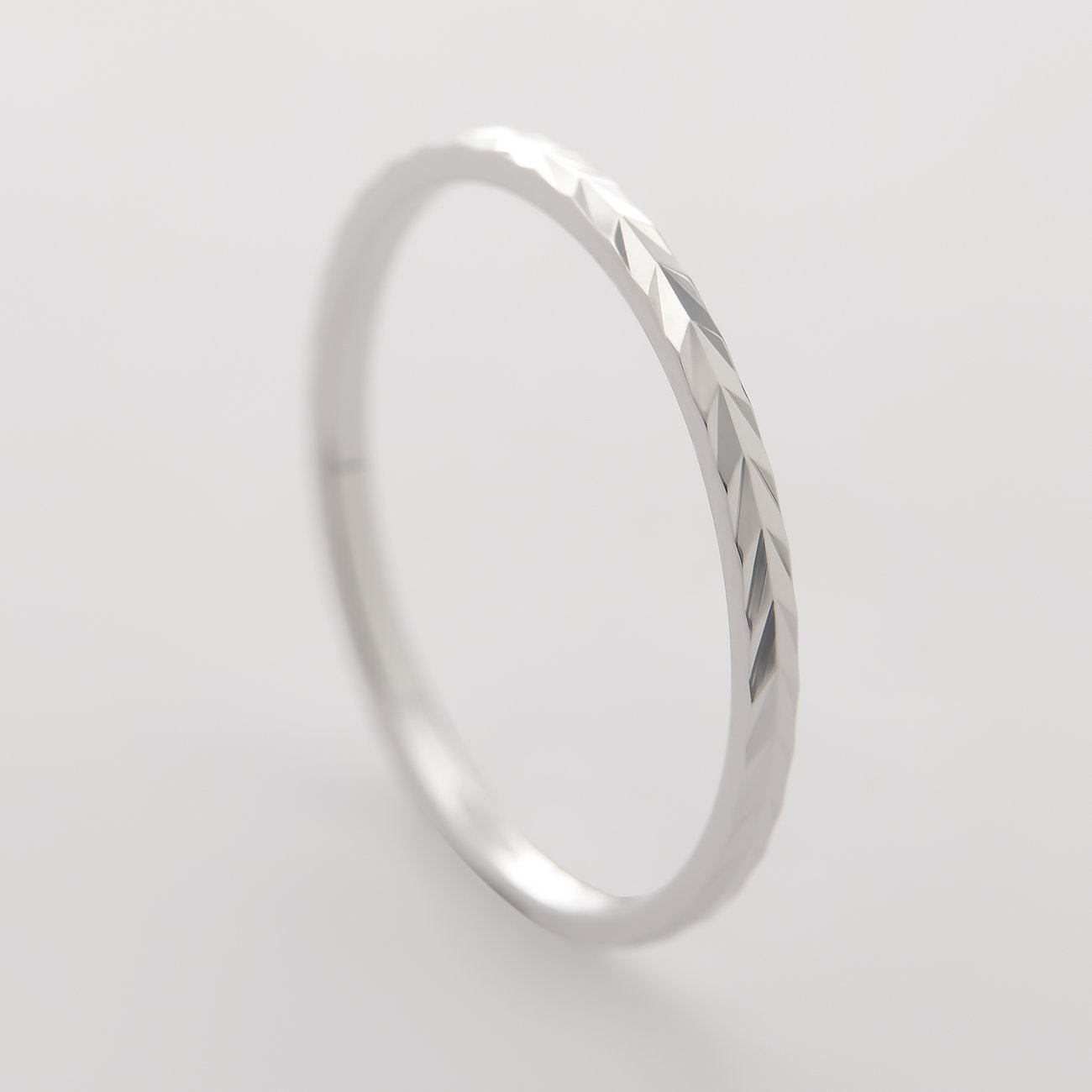 CHRIST-ring i 375 vitguld med filigran fasetterad yta, fotograferad lätt snett uppifrån.