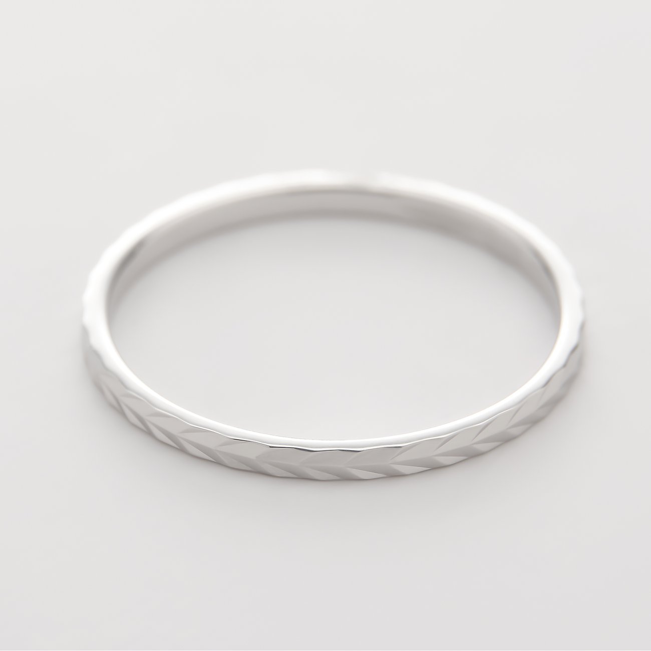 Närbild av en CHRIST-ring i 375 vitguld, snett ovanifrån. Ringen har ett graverat mönster.