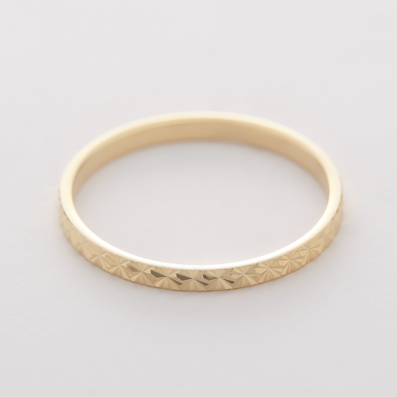 CHRIST Ring aus Gelbgold 375 mit umlaufendem, funkelndem Diamantschliff-Muster, von der Seite aufgenommen.