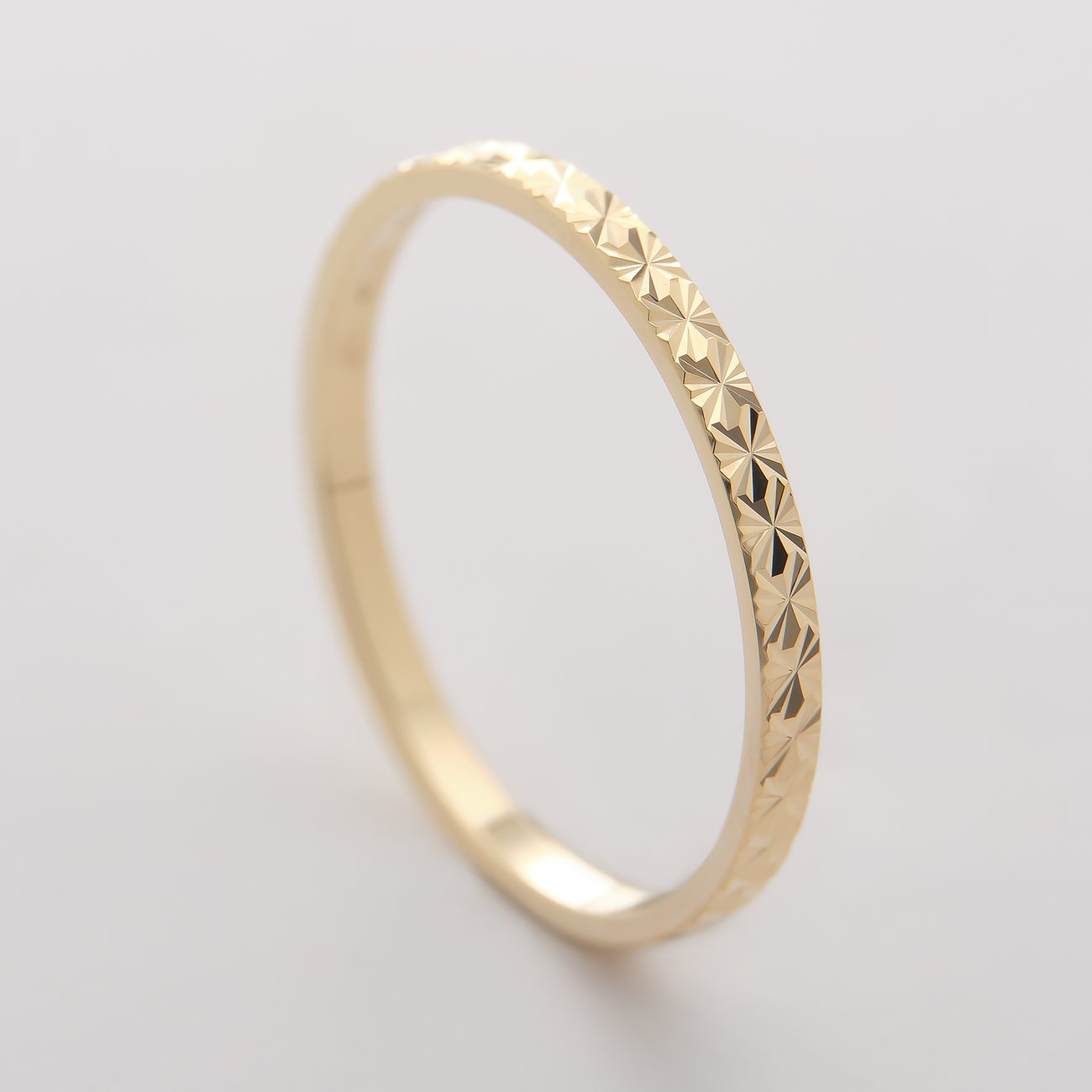 CHRIST Ring aus 375er Gelbgold mit facettiertem Muster, schräg von oben aufgenommen.