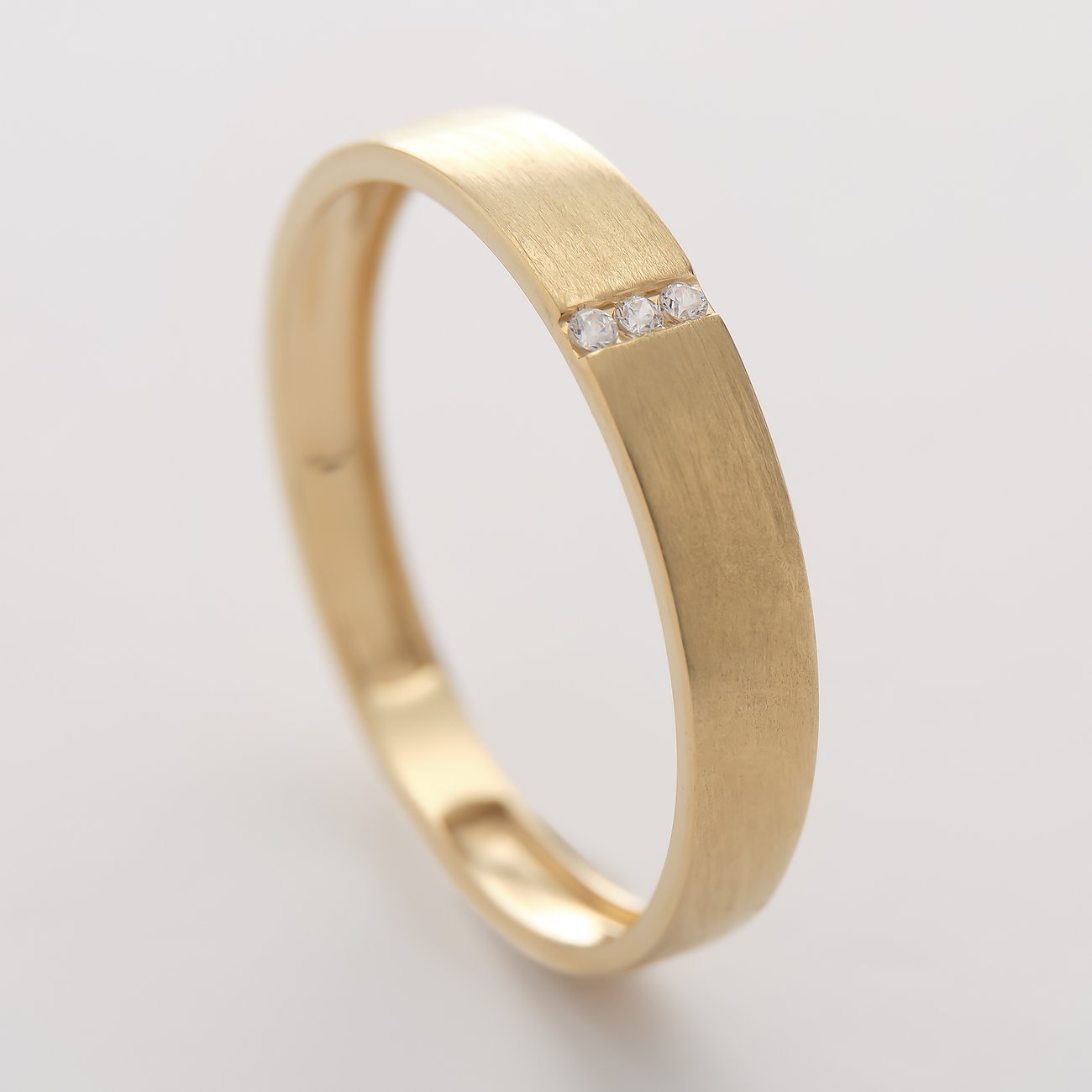 CHRIST ring van geelgoud, mat geborsteld, met drie fonkelende gekleurde zirkoniasteentjes in close-up.