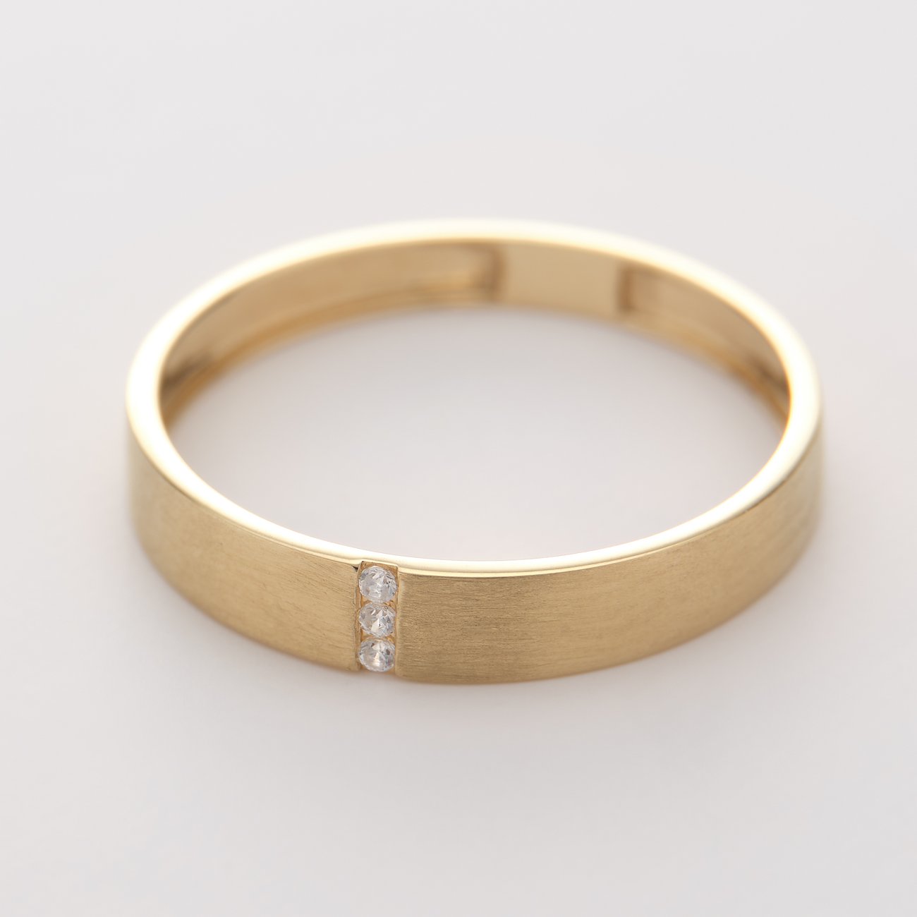 CHRIST 375 geelgouden ring met drie sprankelende zirkonia kleurstenen op een rij, schuin van bovenaf gezien.