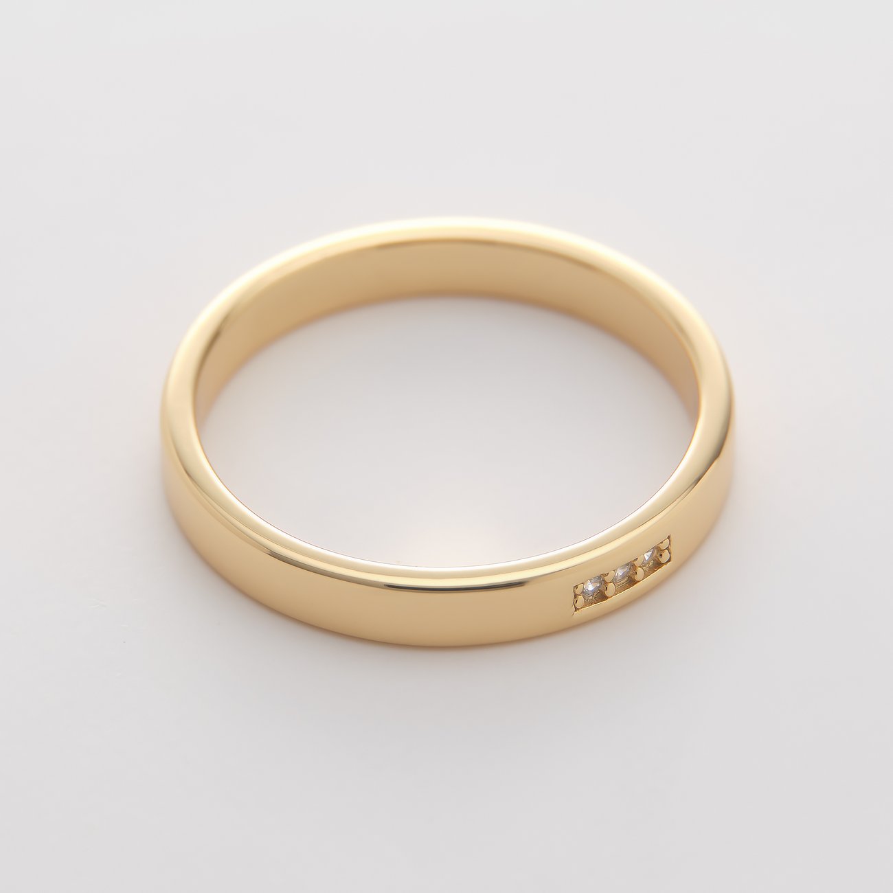 Nahaufnahme eines goldfarbenen CHRIST Rings aus recyceltem Silber mit drei funkelnden Zirkonia-Farbsteinen.