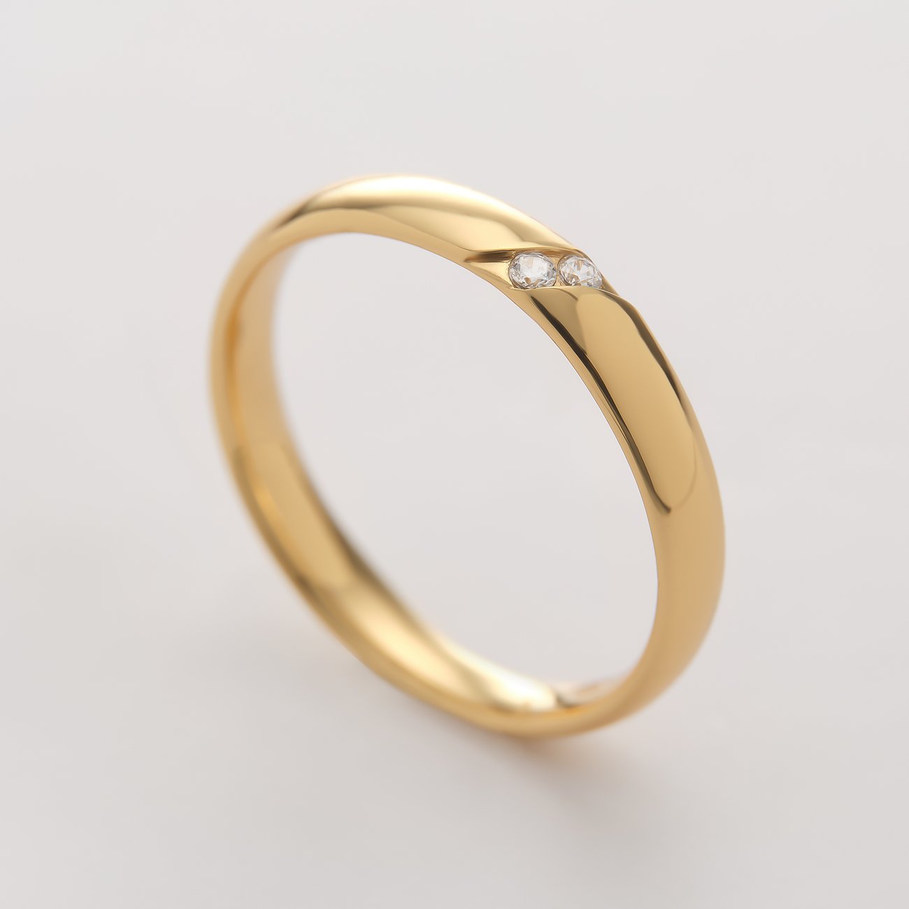 En skinnende, guldfarvet CHRIST ring af genanvendt 925 sølv med to skråt indstillede små zirkonia sten.