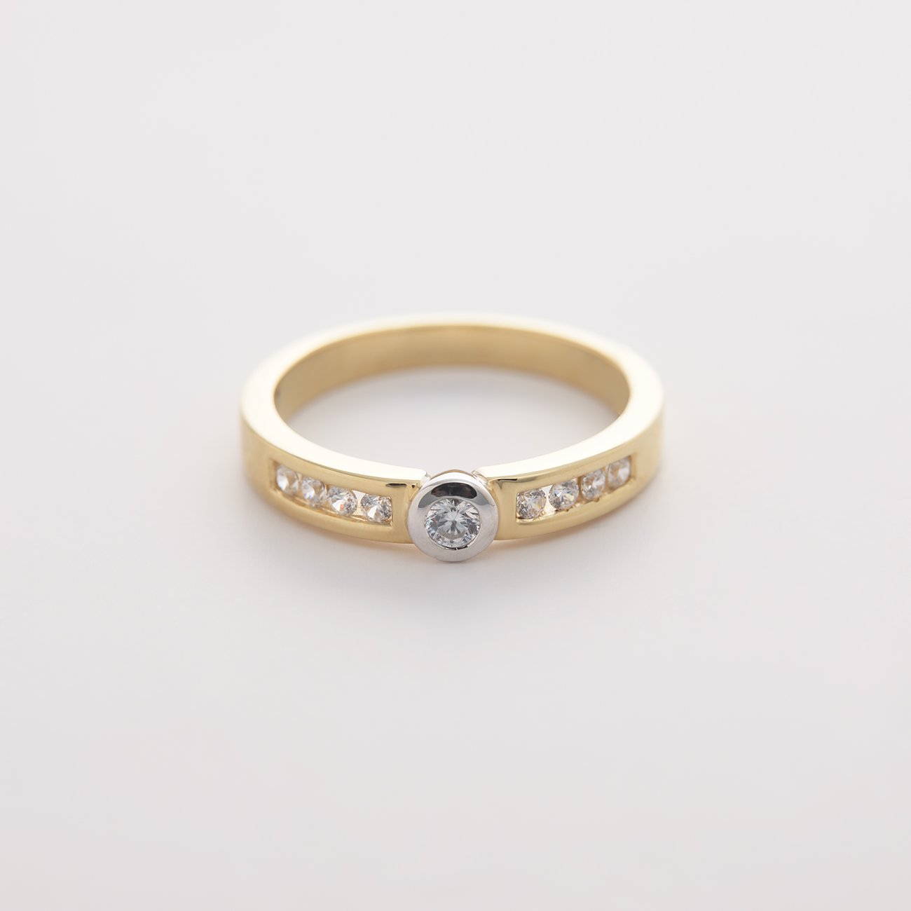 CHRIST-ring i gult och vitt guld med en rundinfattad diamant och flera kanalinfattade diamanter.