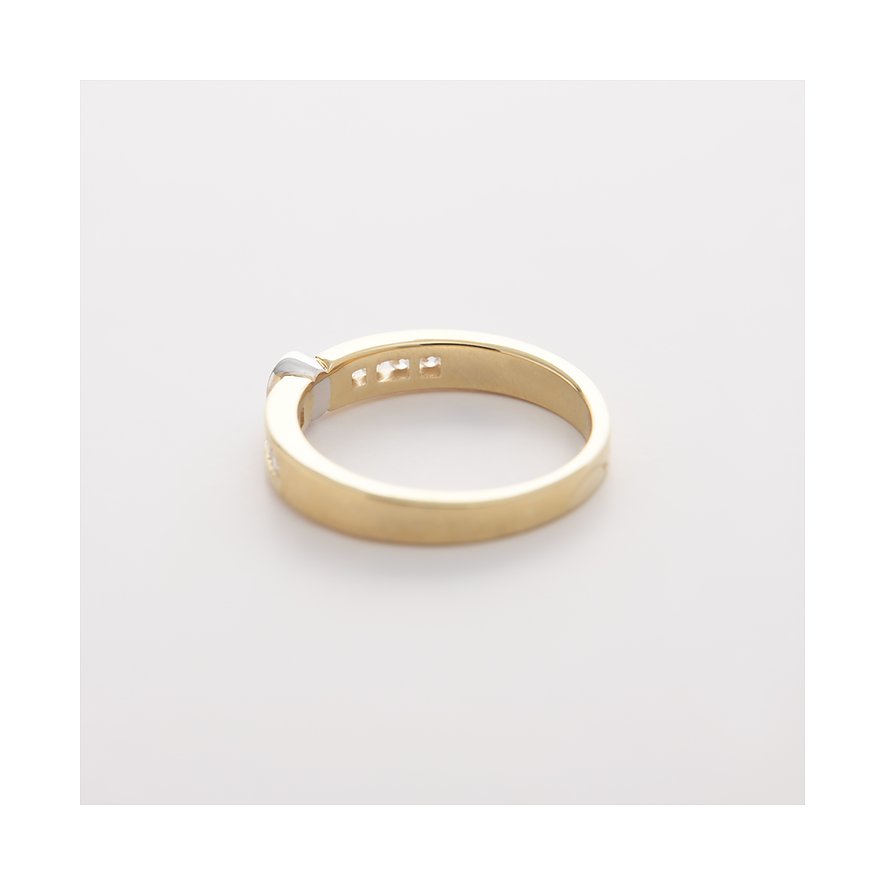 CHRIST-ring i gult och vitt guld med tre gnistrande diamanter på vit bakgrund, tagen snett uppifrån.