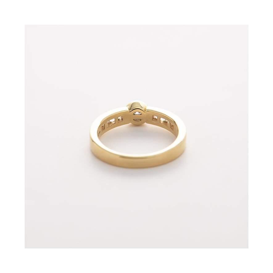 CHRIST Gelbgold-Ring mit einem Diamant in der Mitte und kleineren Diamanten entlang des Bandes, von hinten.