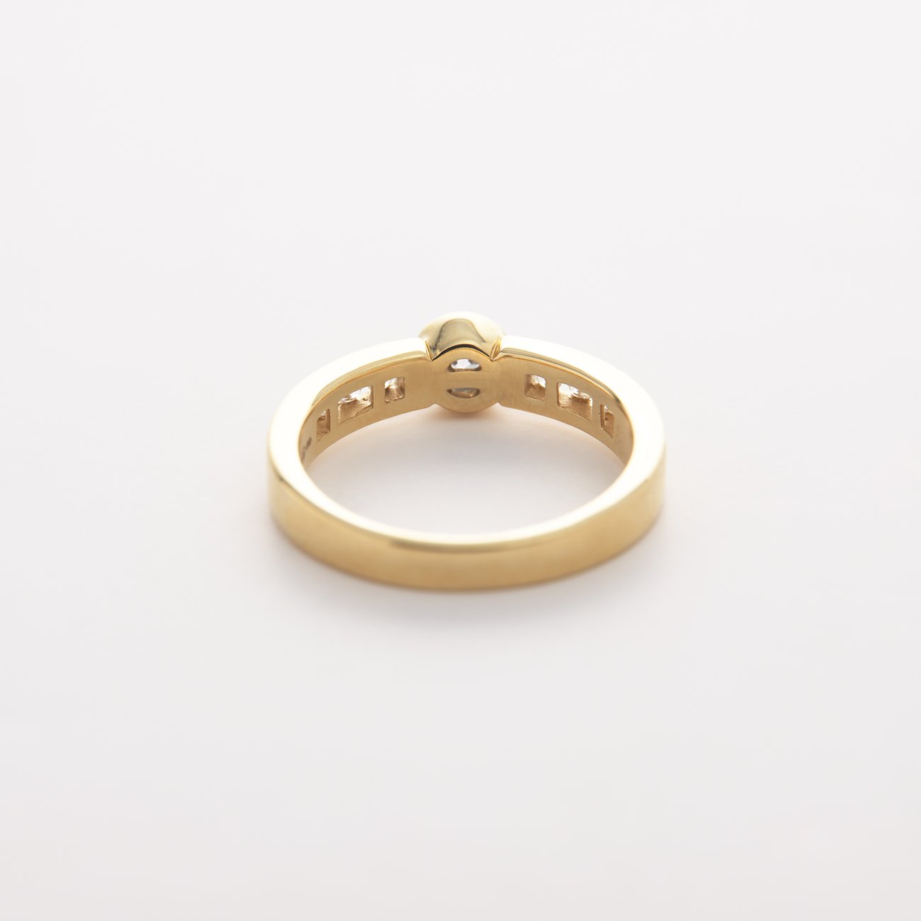 CHRIST Gelbgold-Ring mit einem Diamant in der Mitte und kleineren Diamanten entlang des Bandes, von hinten.