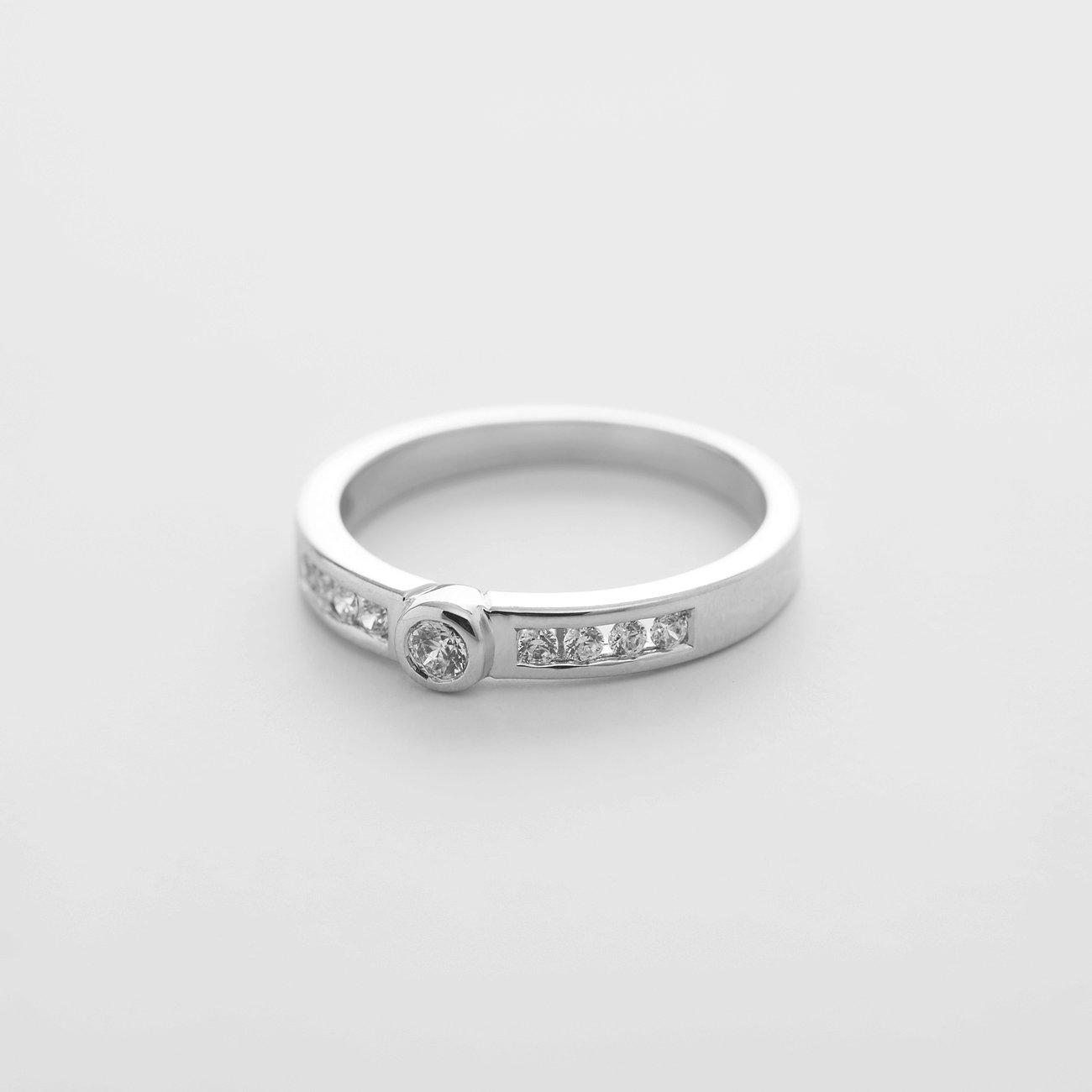 CHRIST Ring aus 585 Weißgold mit einem zentralen runden Diamant und seitlich eingesetzten quadratischen Diamanten.