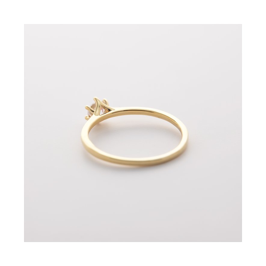 Ein zarter CHRIST Ring aus 585er Gelbgold, seitlich fotografiert, mit einem einzelnen Diamanten in einer Krappenfassung.