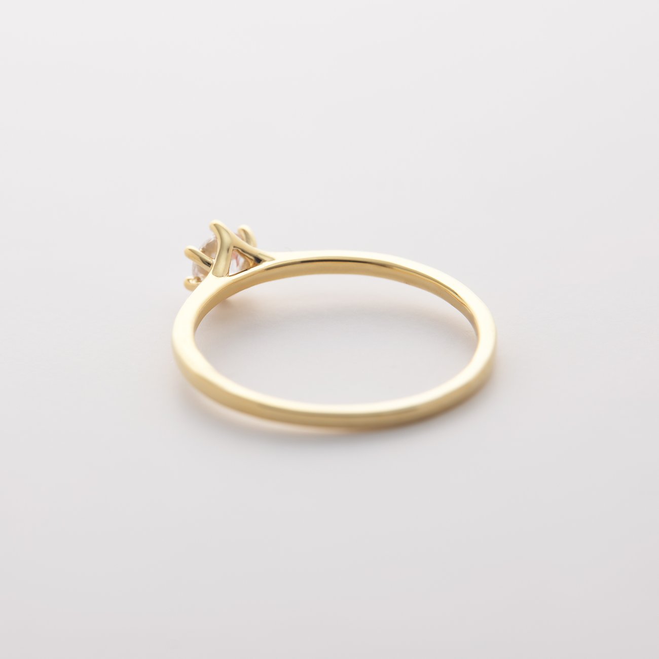Ein zarter CHRIST Ring aus 585er Gelbgold, seitlich fotografiert, mit einem einzelnen Diamanten in einer Krappenfassung.