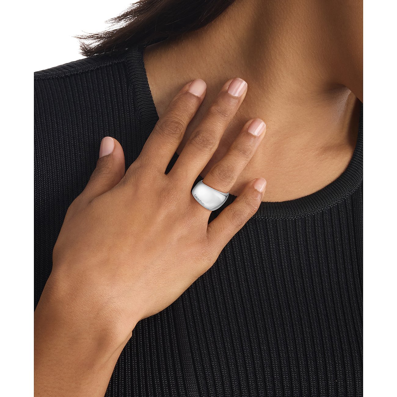 Een brede, zilverkleurige Calvin Klein ring van roestvrij staal wordt gedragen aan iemands ringvinger.