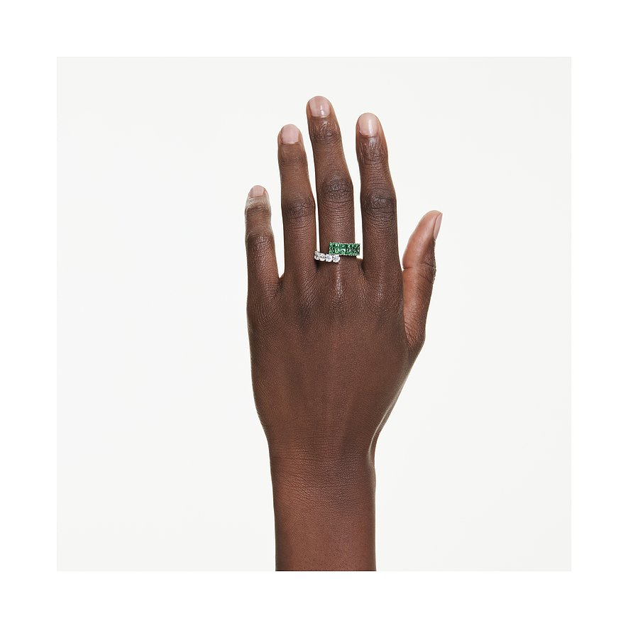Hand trägt einen goldfarbenen Swarovski Ring mit quadratischen grünen Steinen und einen silberfarbenen Ring mit runden klaren Steinen.
