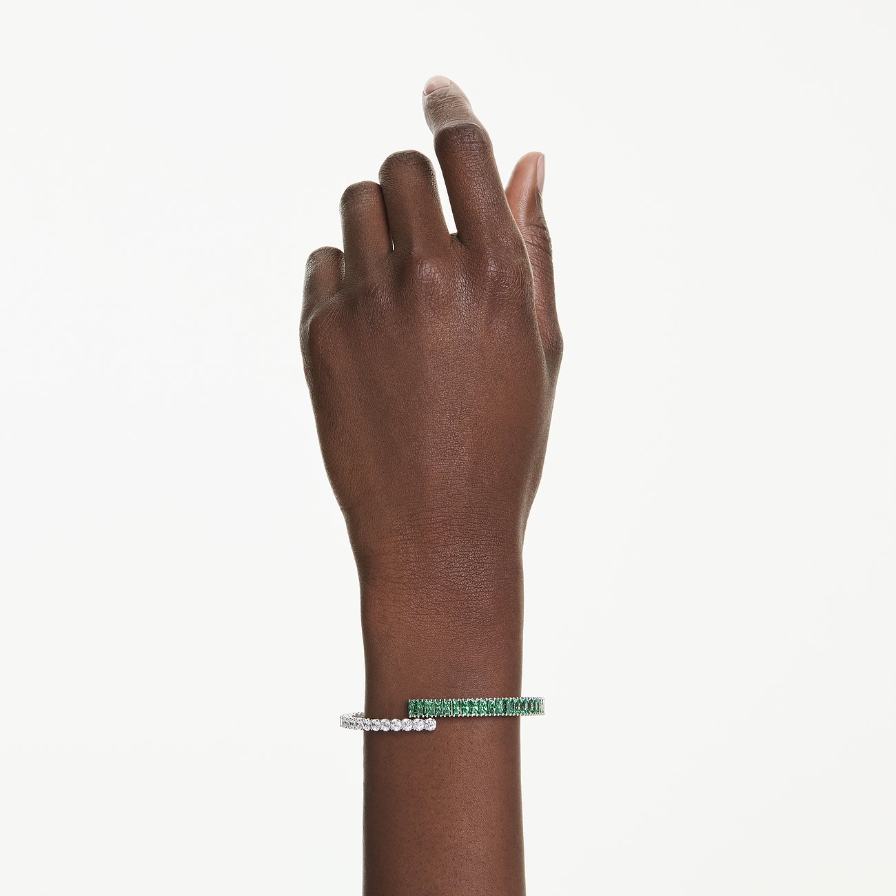 Am Handgelenk getragenes Swarovski Armband aus Metall mit einer Reihe grüner und einer Reihe klarer Swarovski Kristalle.