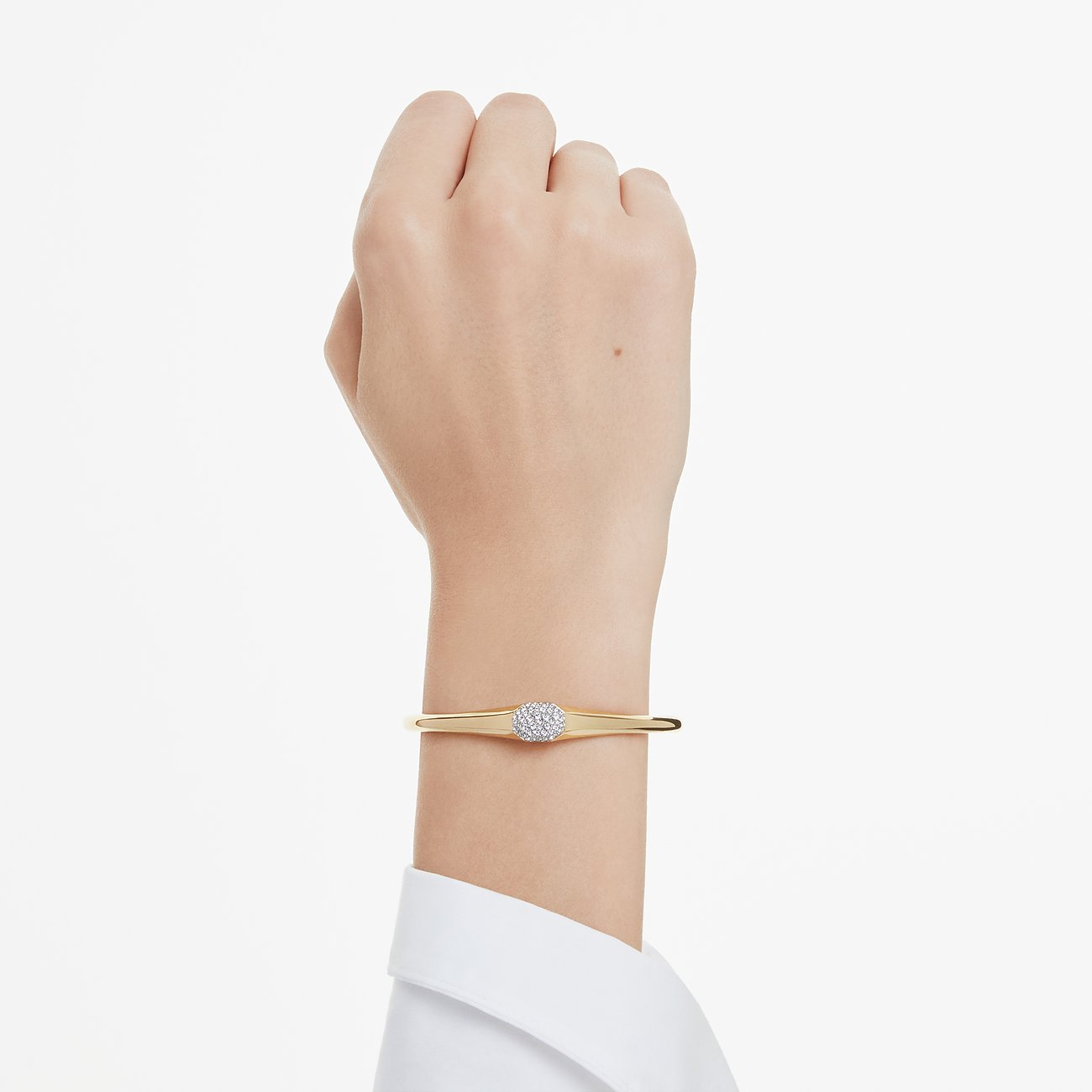 Een goudkleurige Swarovski metalen armband om de pols, met een ronde gekleurde Swarovski-kristal in het midden.