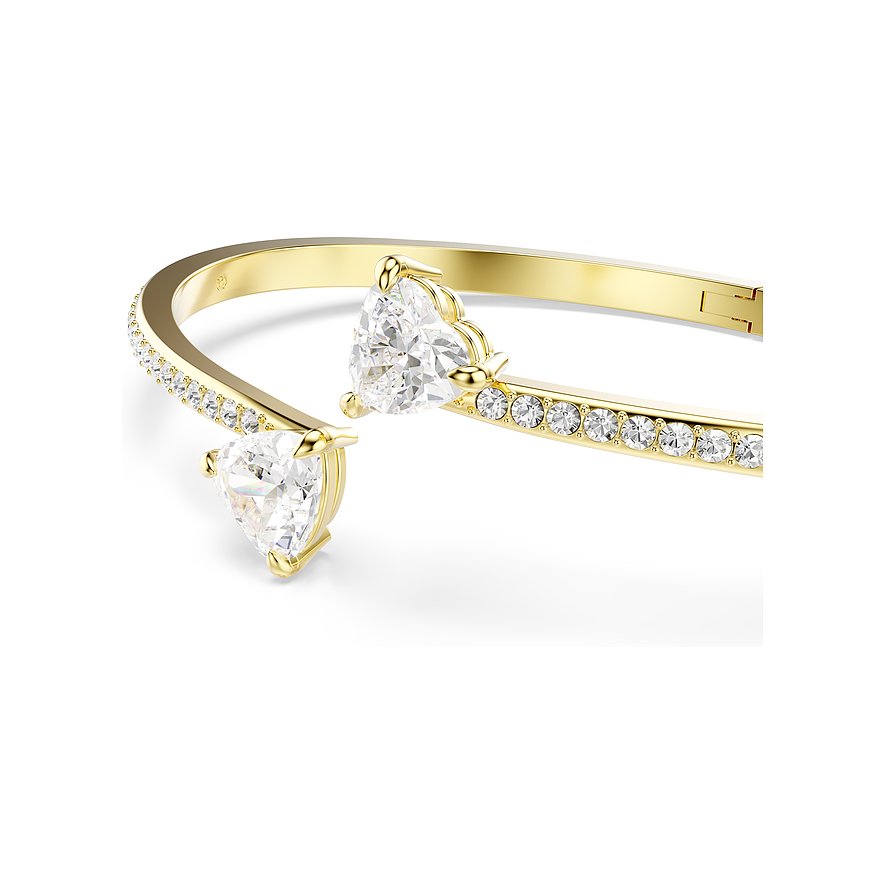 Nahaufnahme eines goldenen Armreifs von Swarovski aus Metall mit zwei herzförmigen und vielen runden Kristallen.