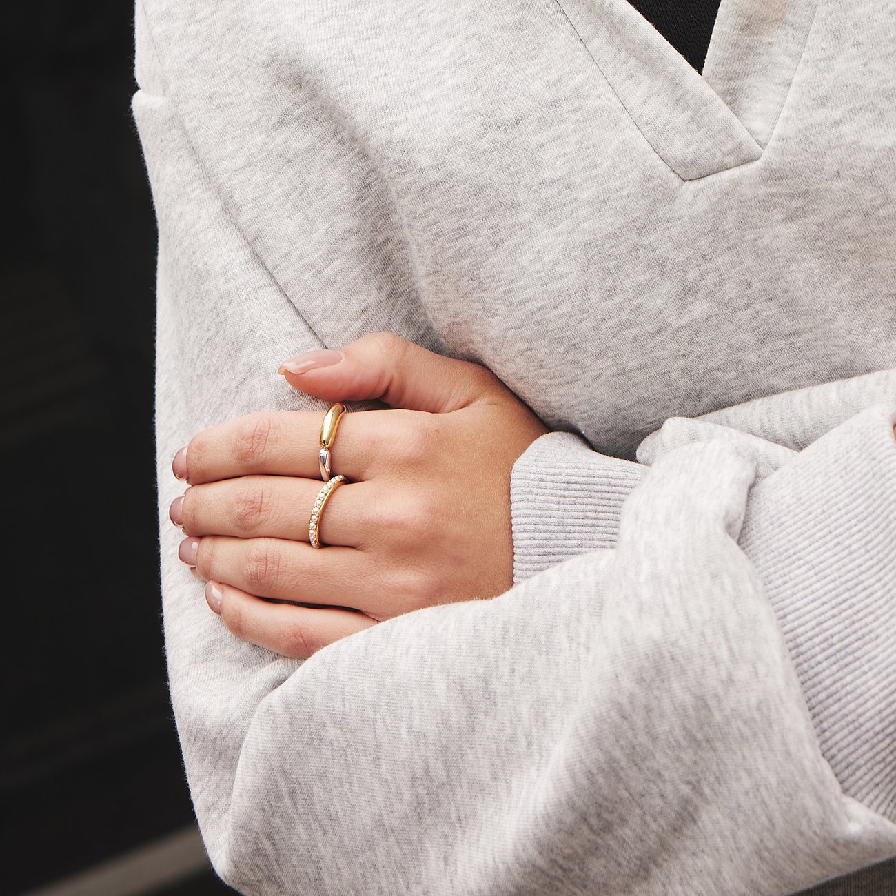 Close-up van iemands handen met twee Ania Haie 925 zilveren ringen met parels.