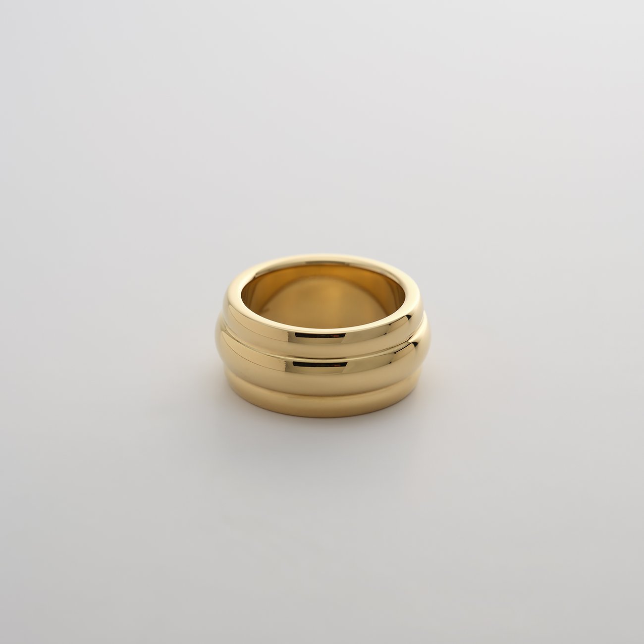 Close-up eines Guido Maria Kretschmer breiten, glänzenden Rings aus goldfarbenem Edelstahl mit zwei erhabenen Rillen.