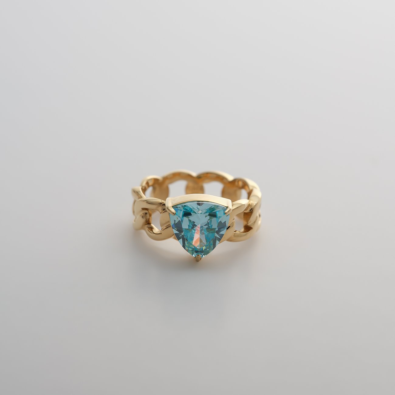 Guido Maria Kretschmer Ring aus goldfarbenem Edelstahl mit hellblauem dreieckigem Zirkonia in der Mitte.