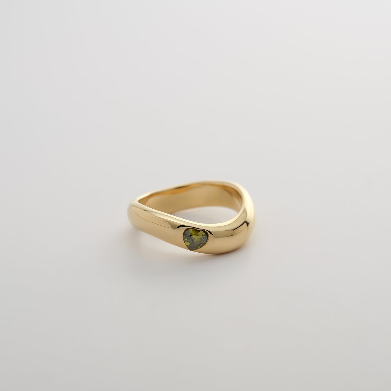Guido Maria Kretschmer ring van goudkleurig edelstaal met golvend design en een groen zirkonia-hart.
