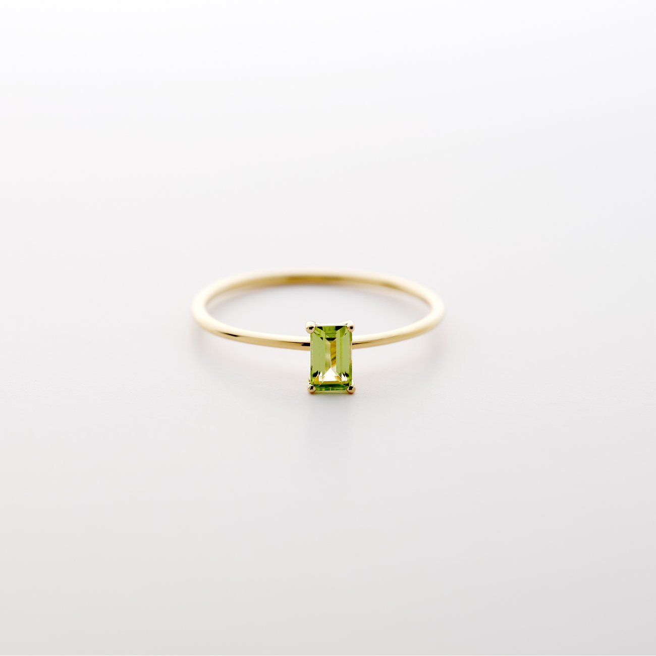 CHRIST ring i 585 gult guld med en rektangulær, lysegrøn peridot i fatning, fotograferet forfra.