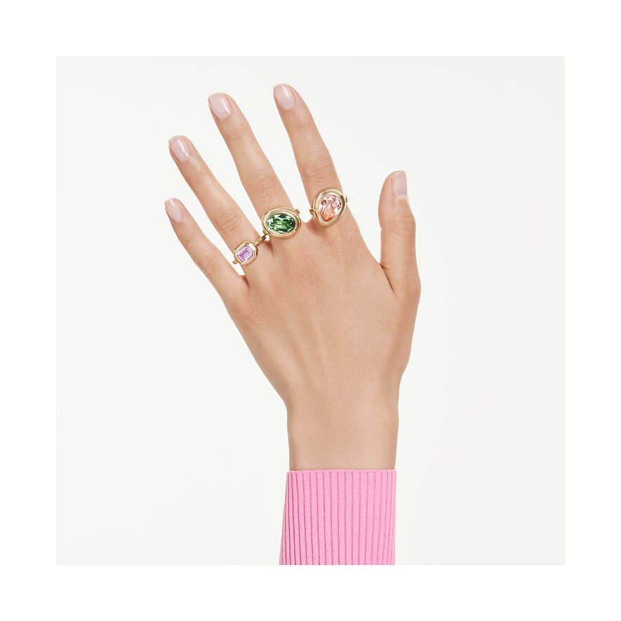Drie metalen Swarovski ringen met meerkleurige Swarovski-kristallen aan een hand. Een paarse ring aan de linker vinger.