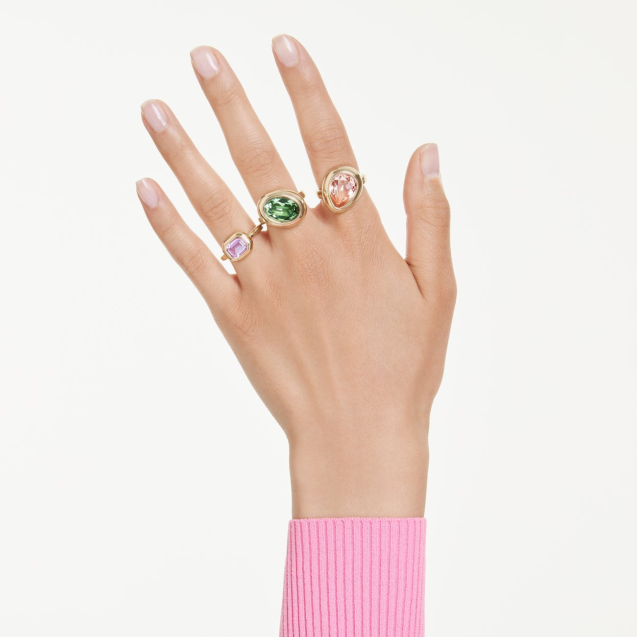 Drie metalen Swarovski ringen met meerkleurige Swarovski-kristallen aan een hand. Een paarse ring aan de linker vinger.