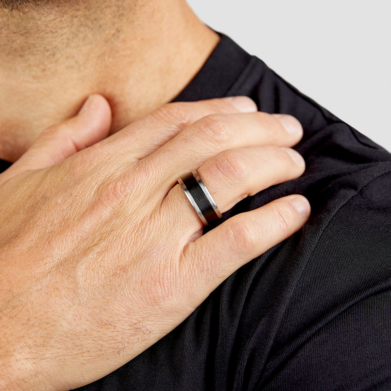 Ein s.Oliver Herrenring aus Edelstahl in Silber und Schwarz wird an einem Finger eines Mannes getragen.